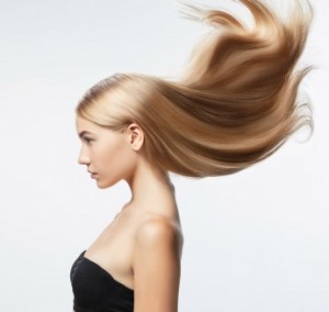 Beautiful model with long smooth, flying blonde hair isolated on white studio background. Young caucasian model with well-kept skin and hair blowing on air. Concept of salon care, beauty, fashion.